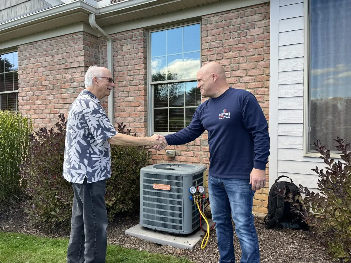 Ryan from Foster's Heating & Air shaking hands with a customer next to a new air conditioner